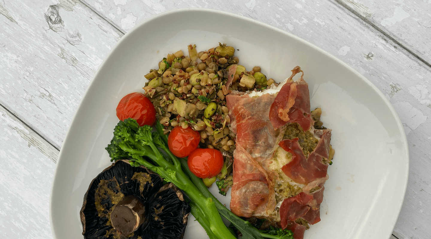 Parma Ham Wrapped Cod on a plate served with broccoli, cherry tomatoes and a large mushroom