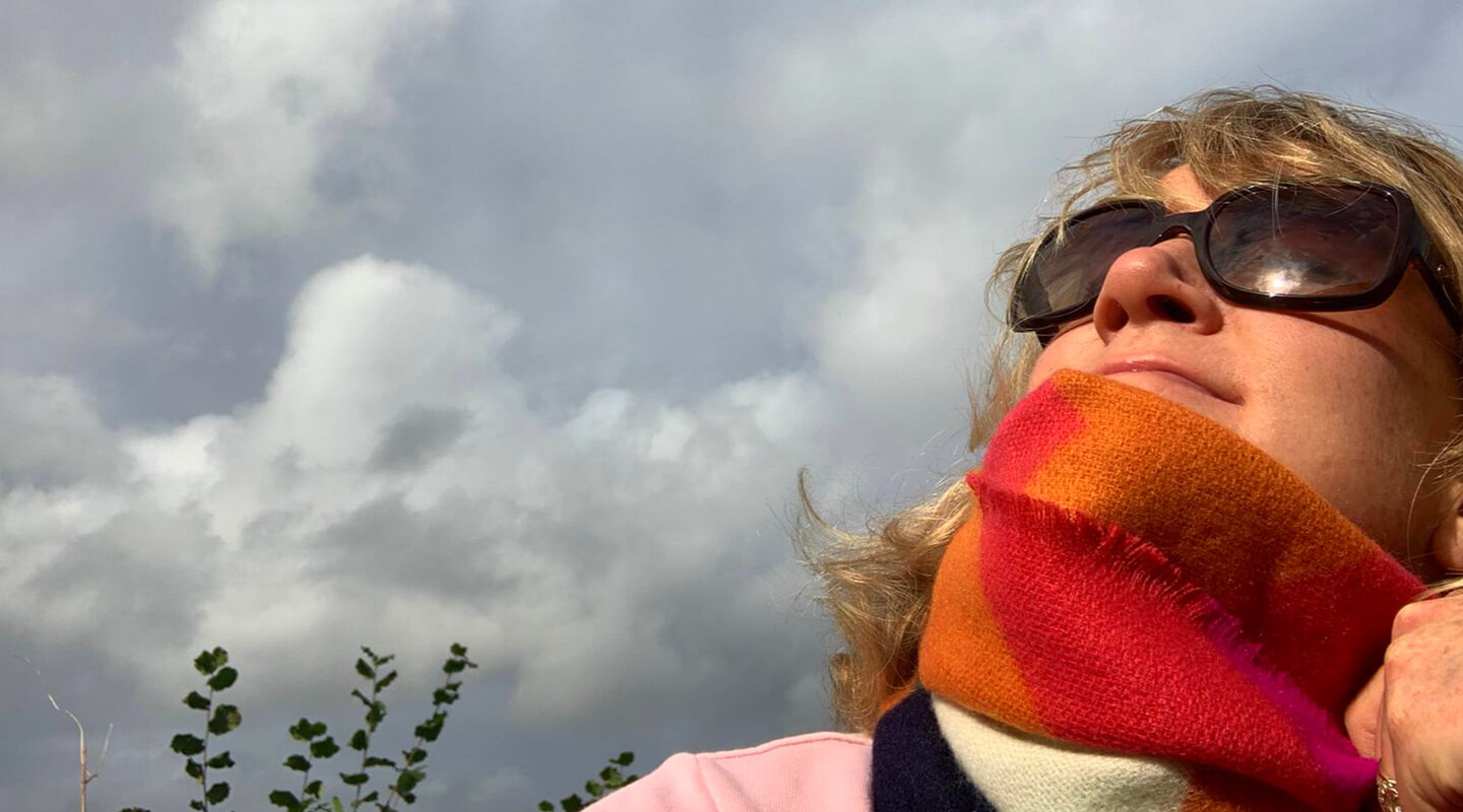 A woman in sunglasses and a scarf making sure she gets enough Vitamin D even in cold weather