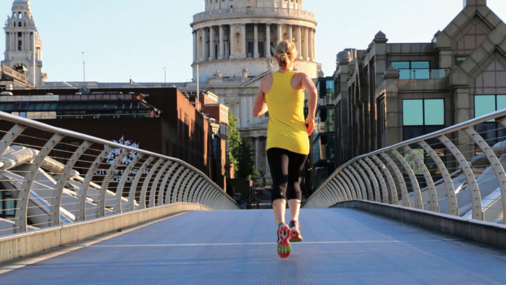 Blonde woman in sportswear power walking across a bridge in London
